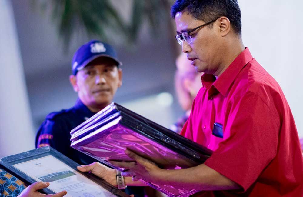 A man in a red shirt is holding a piece of paper.