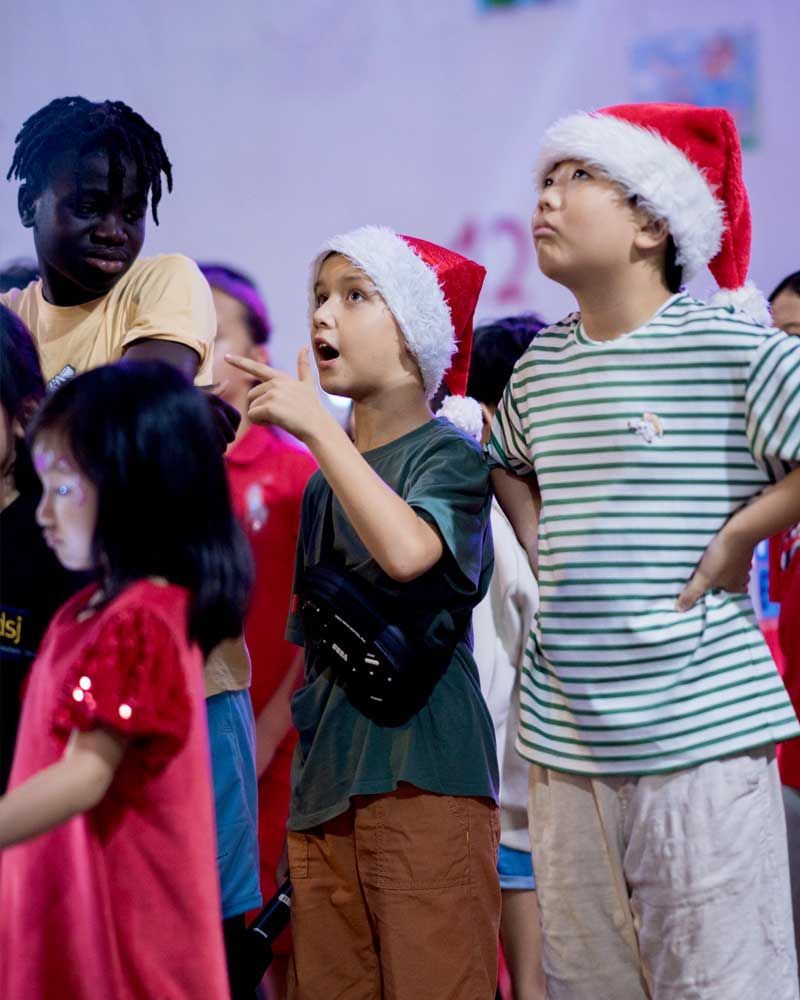 A group of children wearing santa hats and striped shirts