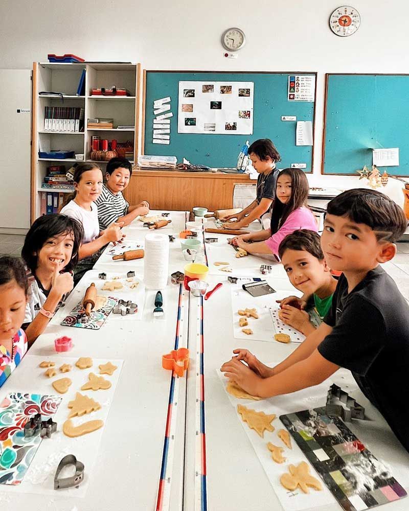 A group of children are sitting around a table making cookies.