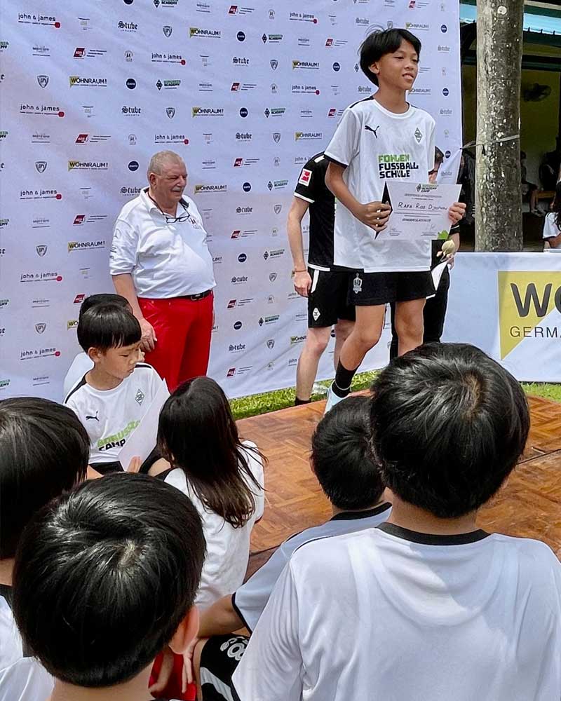 A group of people are sitting in front of a wall that says w germ