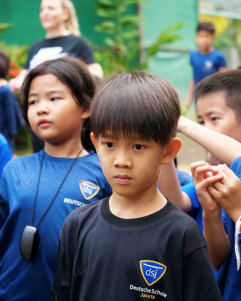 A group of children wearing blue shirts are standing in a line.