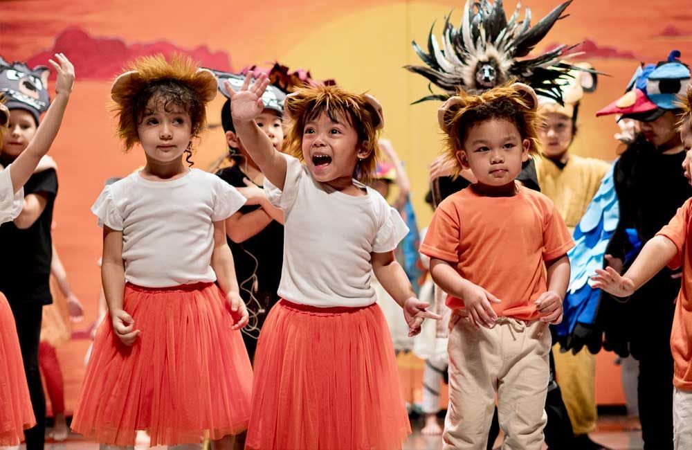 A group of children dressed in costumes are dancing on a stage.