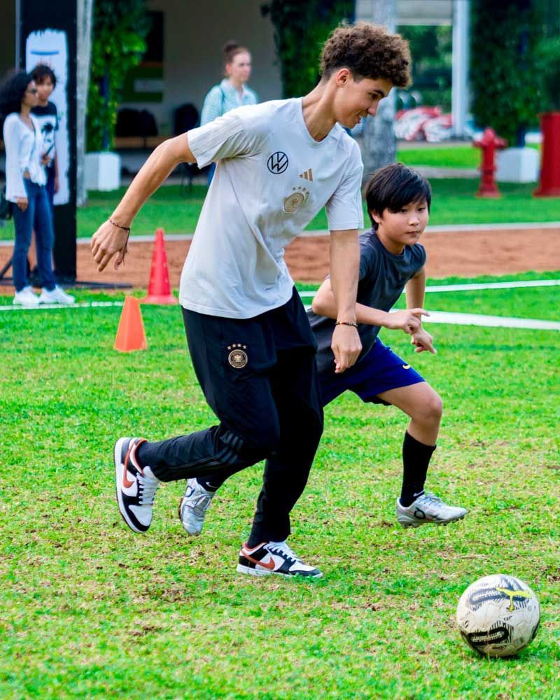A man and a boy are playing soccer on a field.