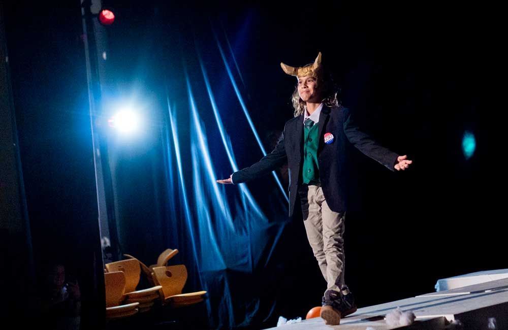 A man in a suit and horned hat is standing on a stage.
