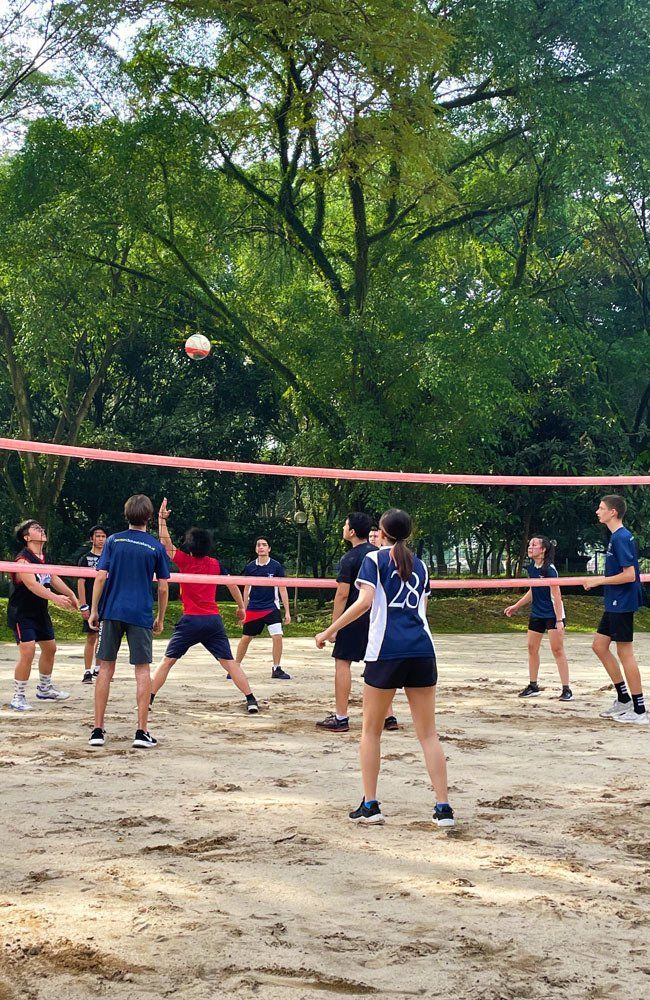 A group of people are playing volleyball on a sandy court.