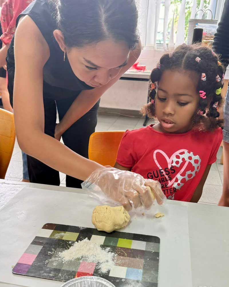 A woman is teaching a little girl how to make dough