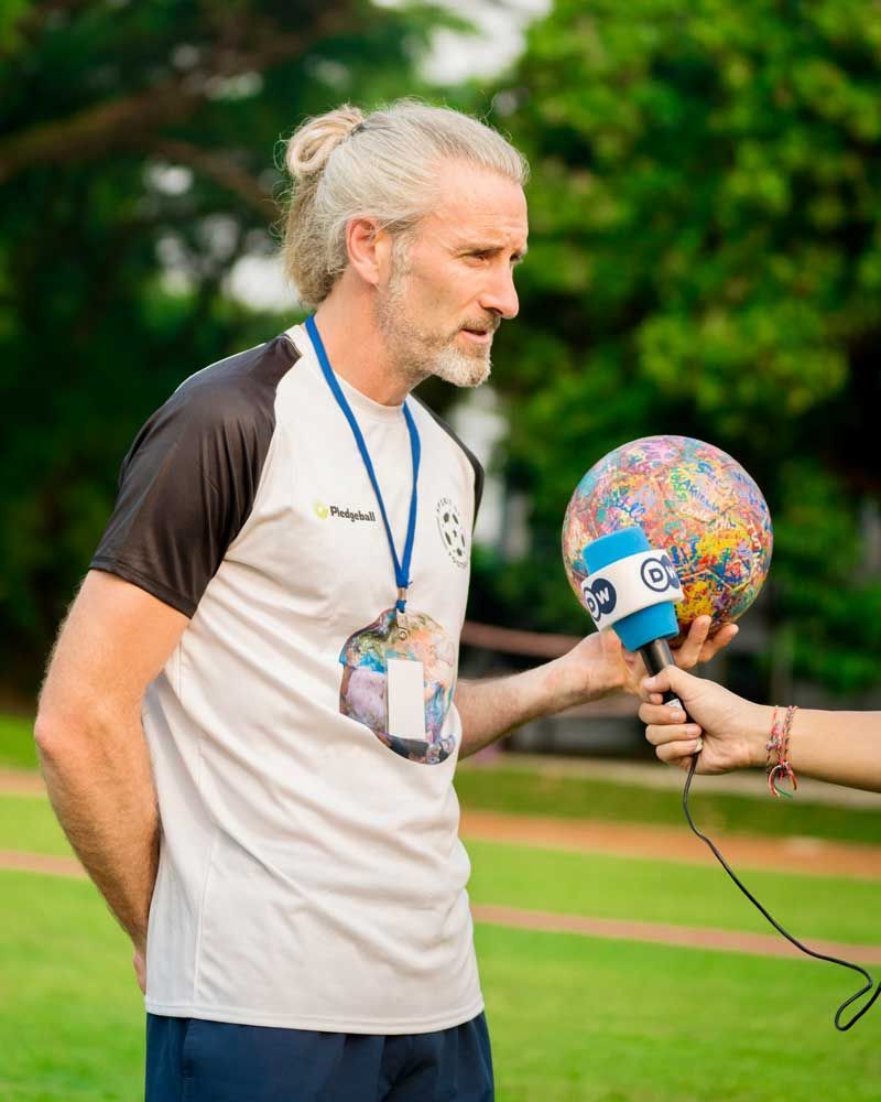 A man is being interviewed with a microphone while holding a globe.