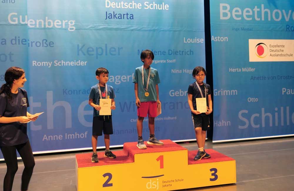 A group of young boys are standing on a podium holding medals.