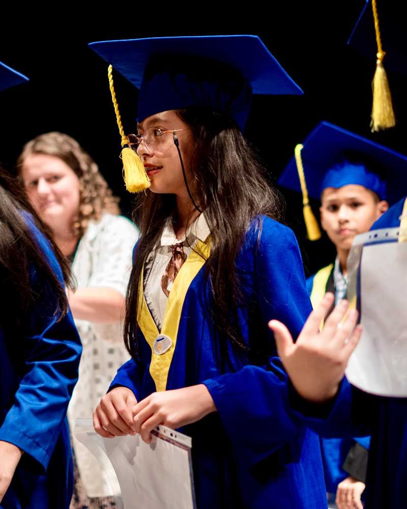 A girl in a graduation cap and gown is holding a diploma