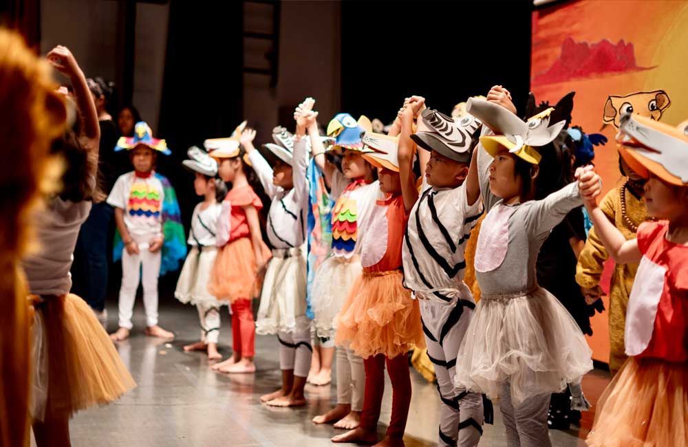 A group of children dressed in costumes are dancing on a stage.