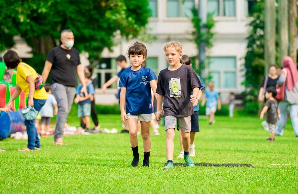 A group of children are walking on a lush green field.