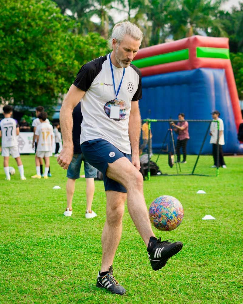 A man is kicking a soccer ball on a field.