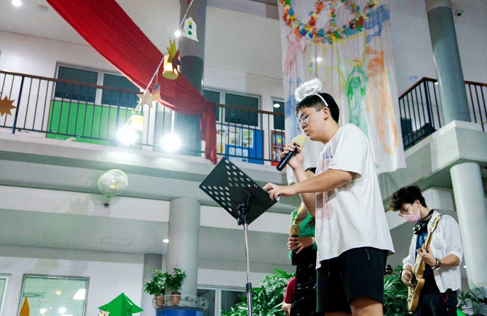 A man is singing into a microphone while another man plays a guitar.