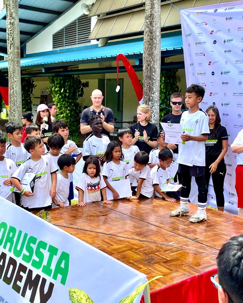 A group of children are standing on a stage in front of a banner that says russia academy.