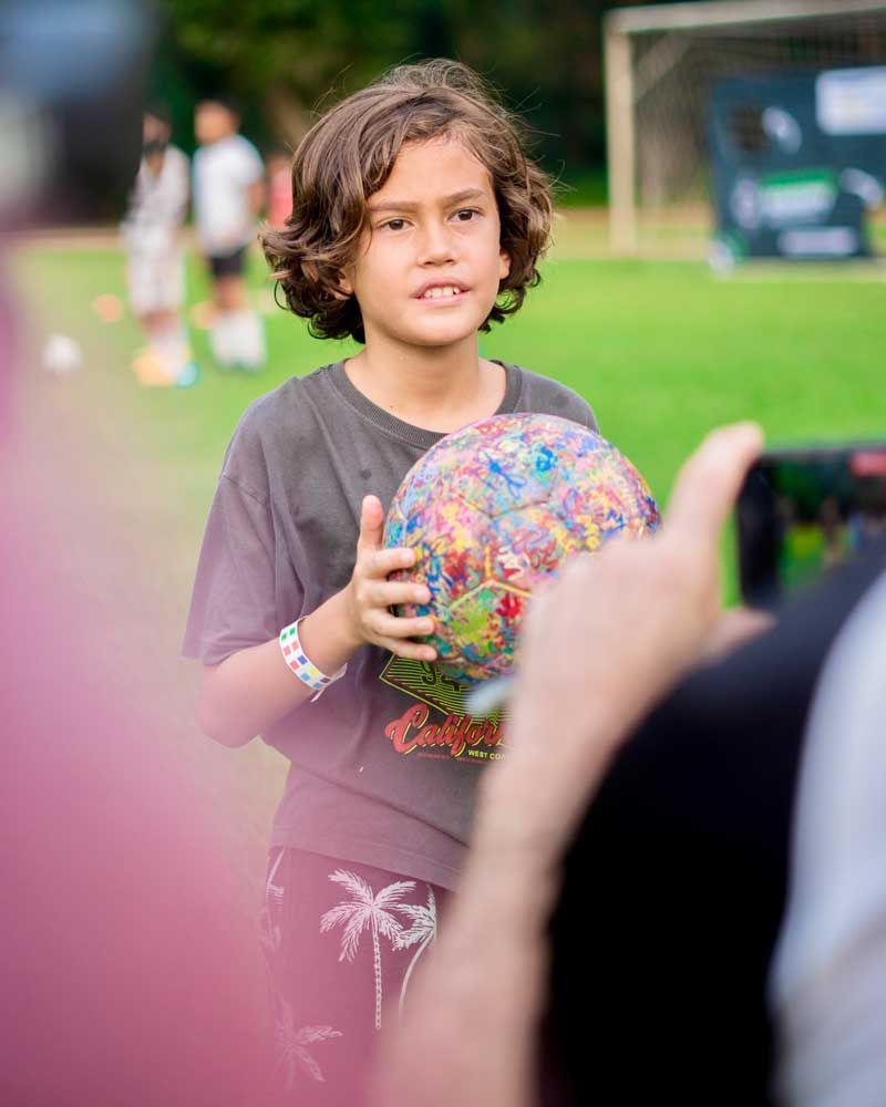 A young boy is holding a soccer ball on a field.