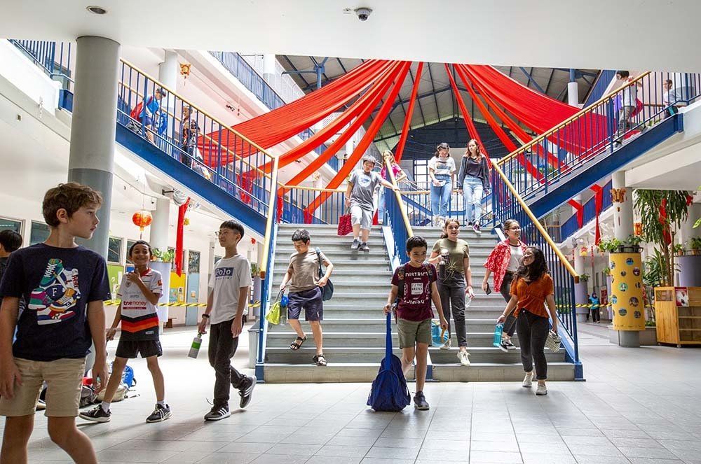 A group of children are walking down stairs in a school building.
