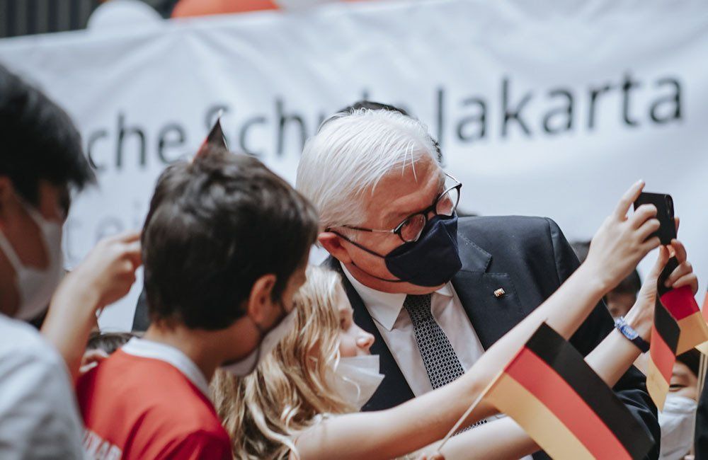 A man wearing a mask is taking a picture of a woman holding a german flag.
