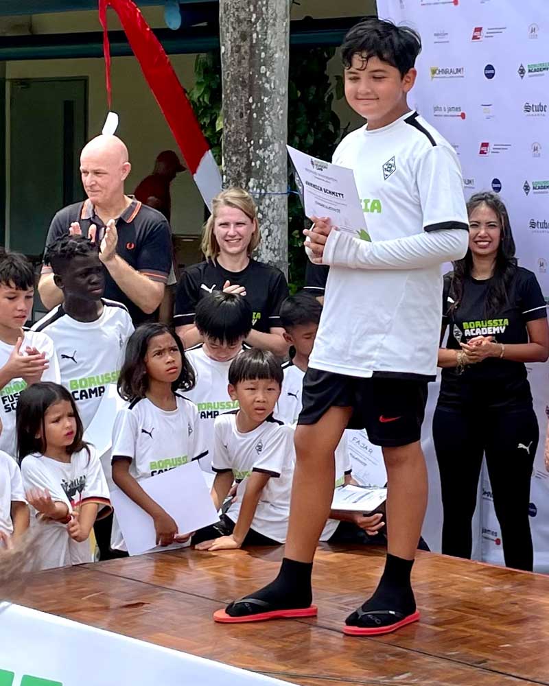 A young boy is standing on a stage holding a piece of paper.