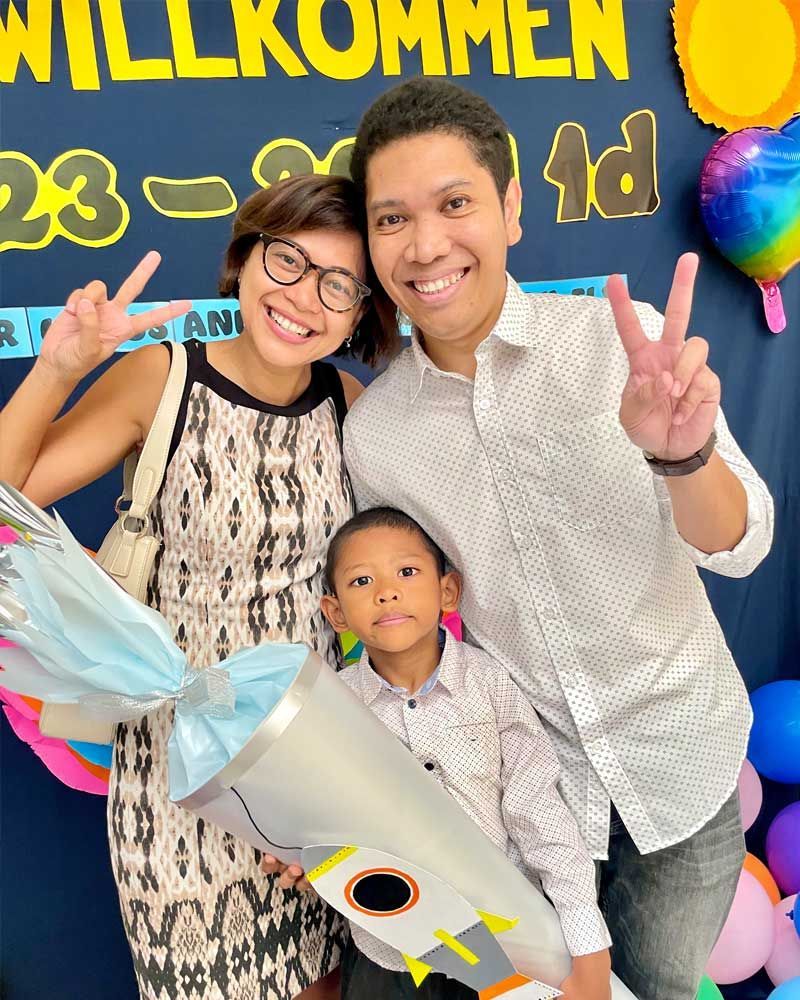 A family is posing for a picture in front of a sign that says willkommen