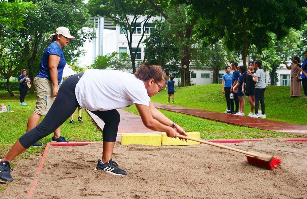 A woman is sweeping the ground with a broom in a park.