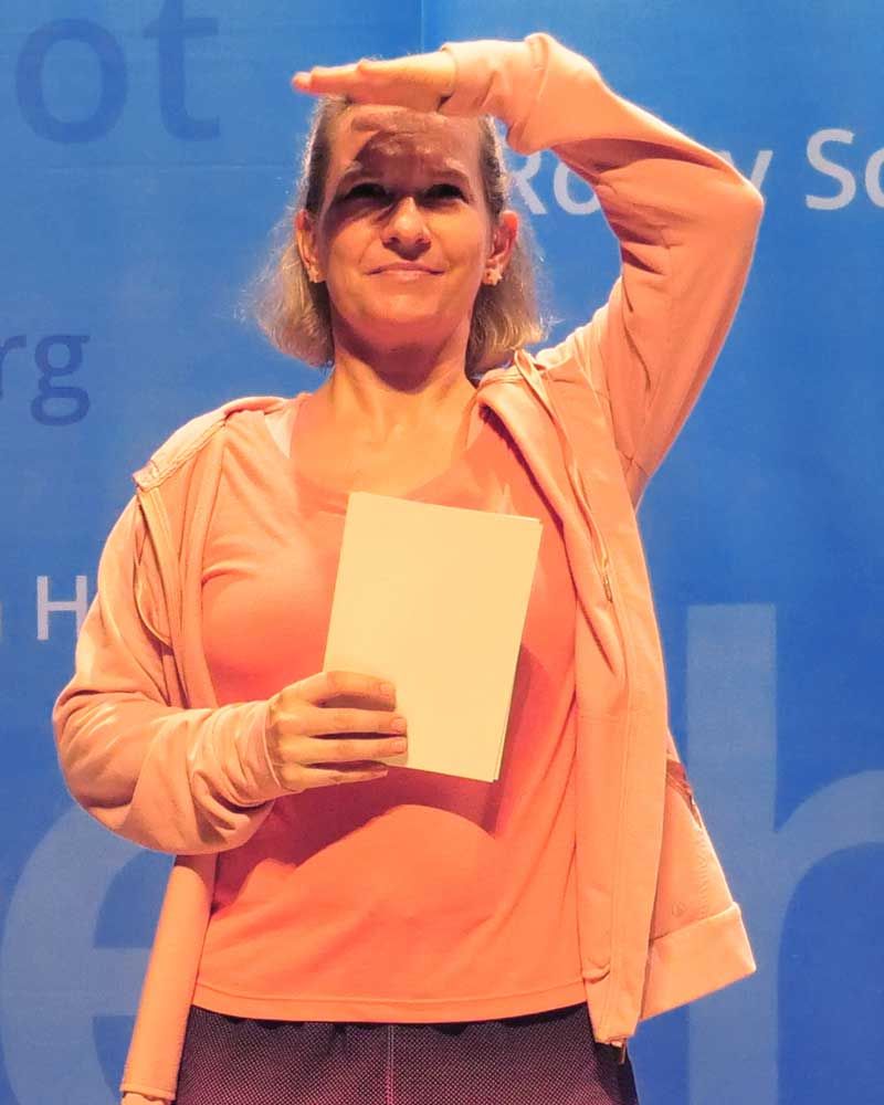 A woman in a pink jacket is holding a piece of paper