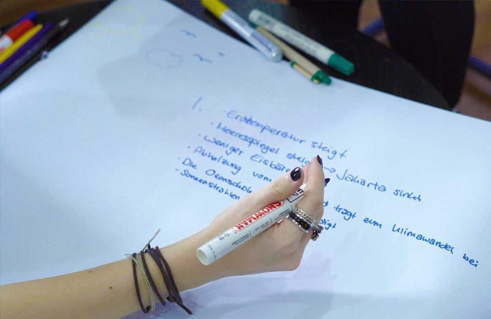 A person is writing on a piece of paper with a marker