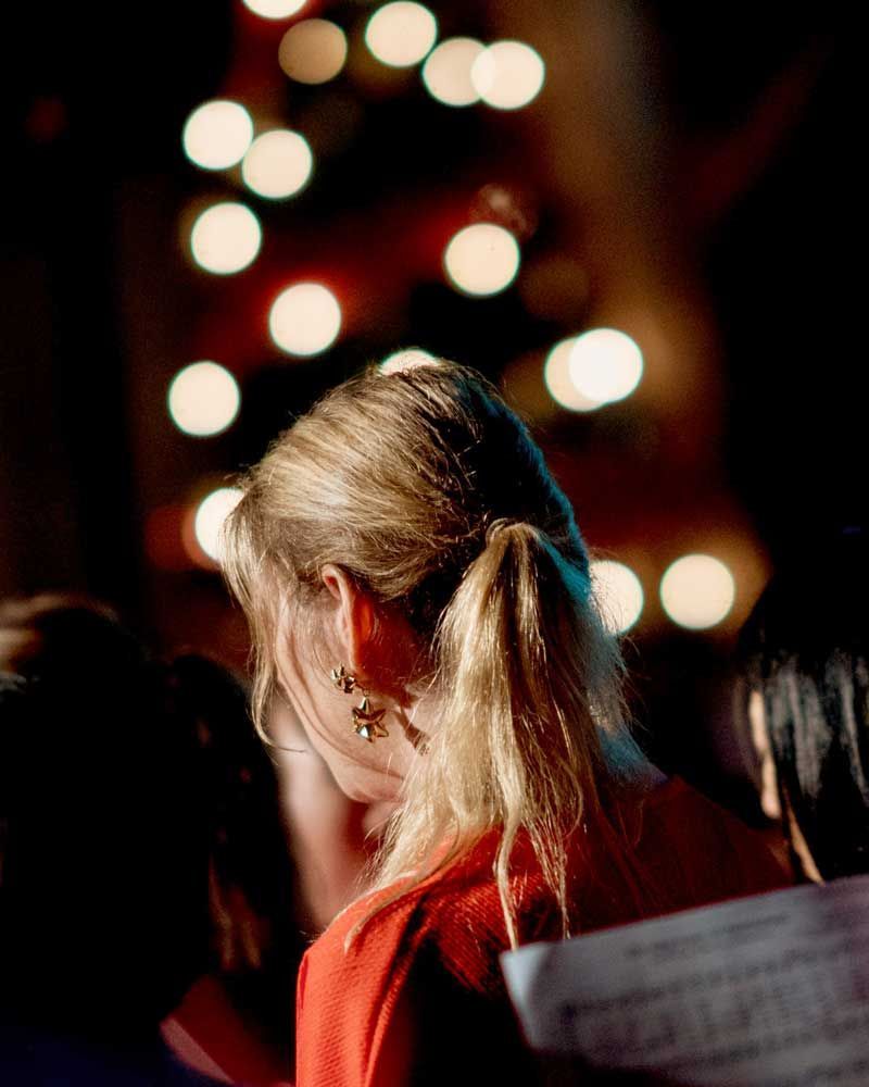 A woman in a red dress is singing in front of a christmas tree.