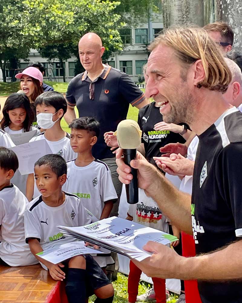 A man is holding a microphone in front of a group of children.