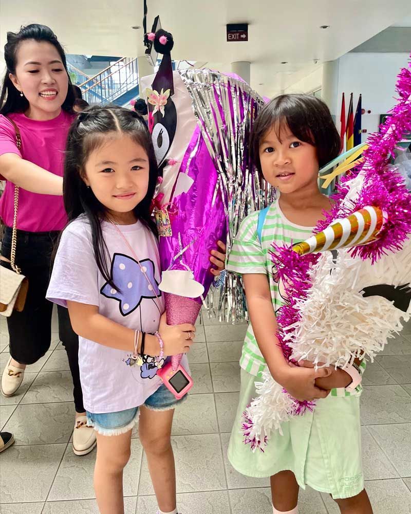 Two little girls are standing next to each other holding balloons.