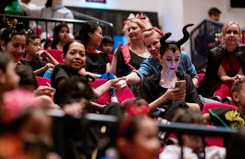A group of people in costumes are sitting in a theater.