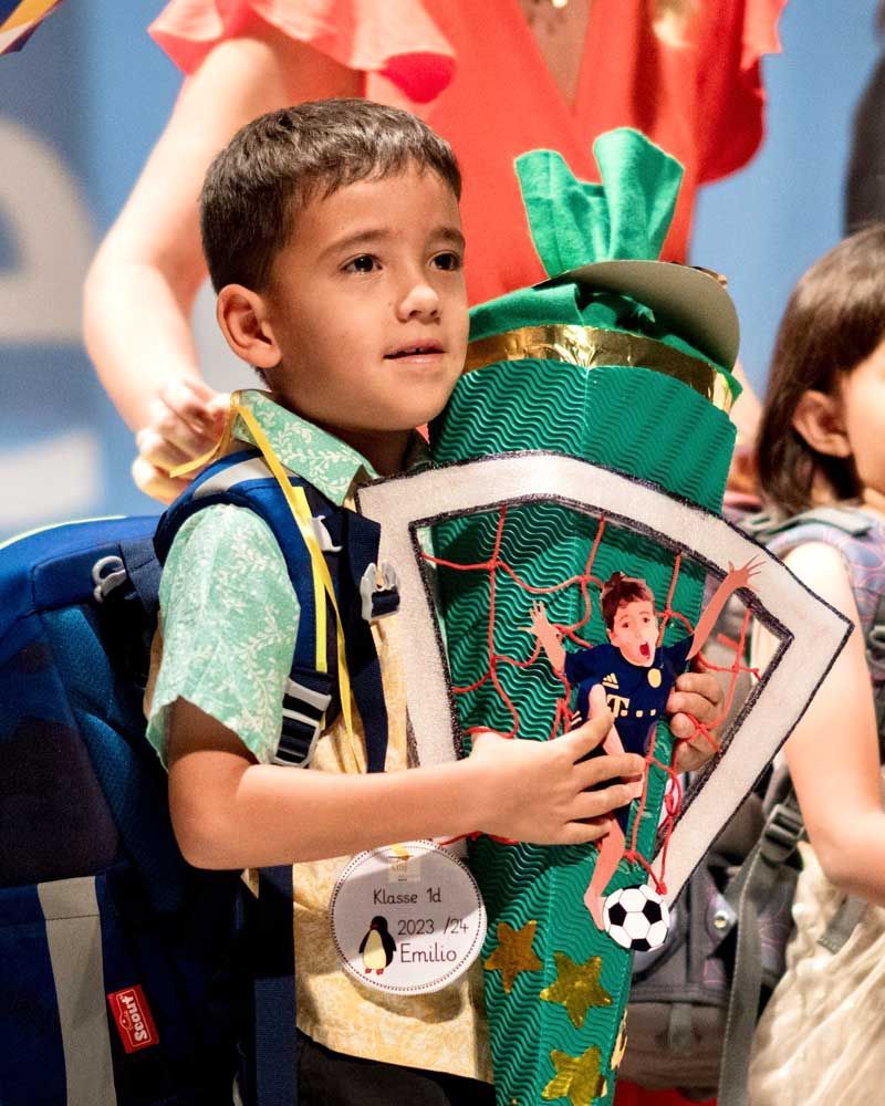 A young boy is holding a green cone with a picture of a soccer player on it.