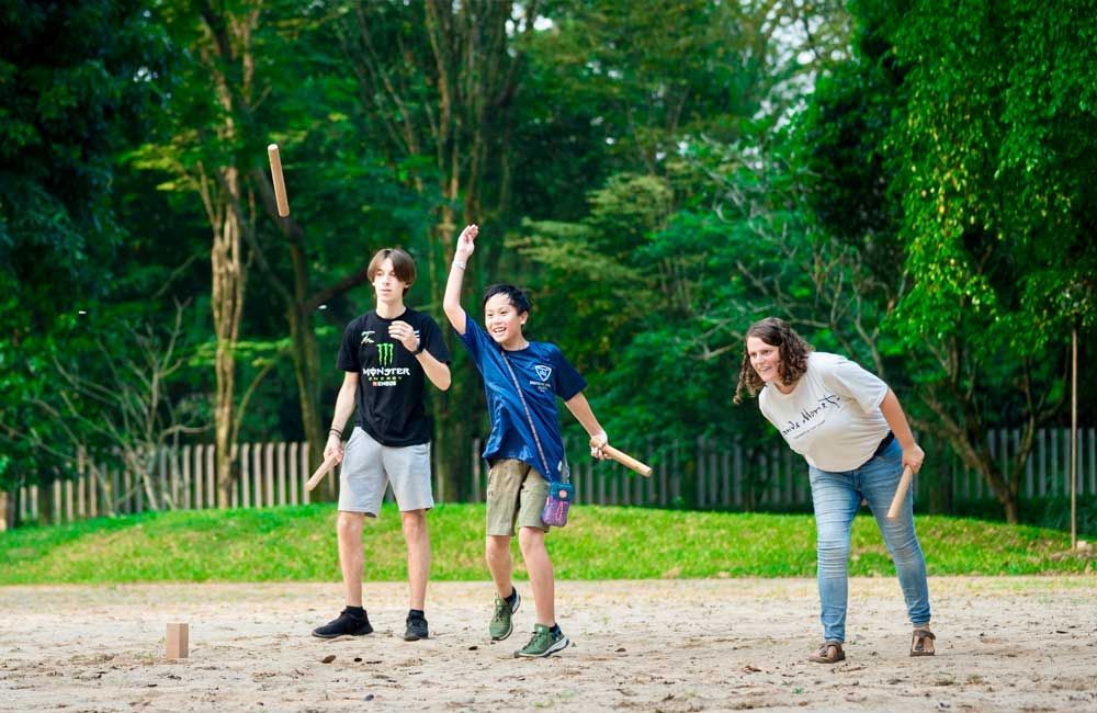 A woman and two children are playing a game in a park.