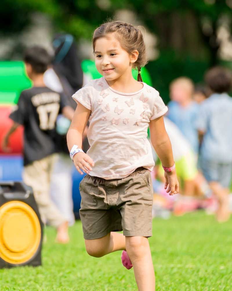 A little girl is running in a field with other children.
