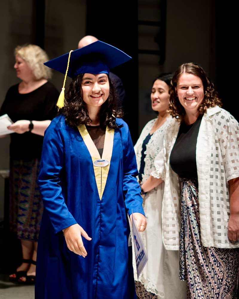 A woman wearing a blue graduation cap and gown