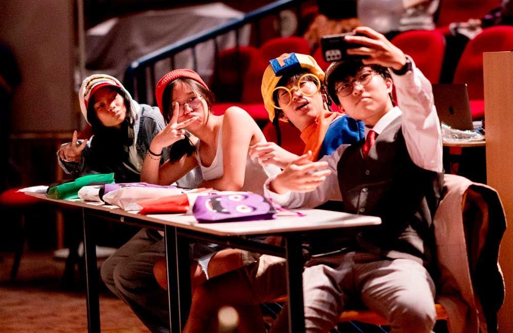 A group of people are sitting at a table taking a selfie.