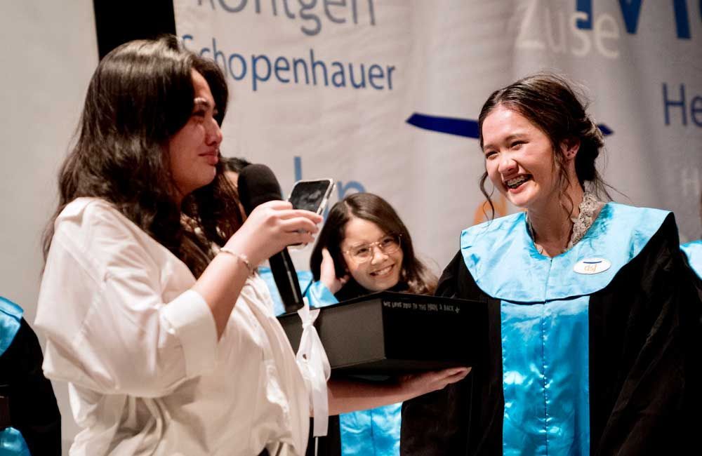 Two women are standing next to each other in front of a sign that says schopenhauer