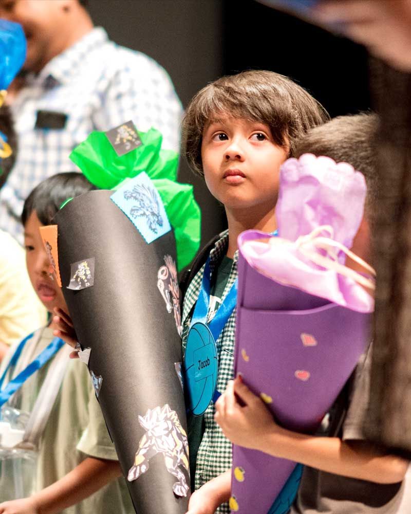 A boy is holding a purple cone with a gift in it