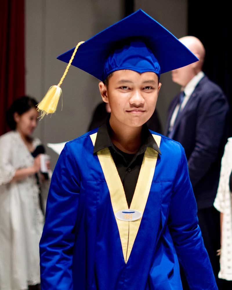 A young boy wearing a blue graduation cap and gown