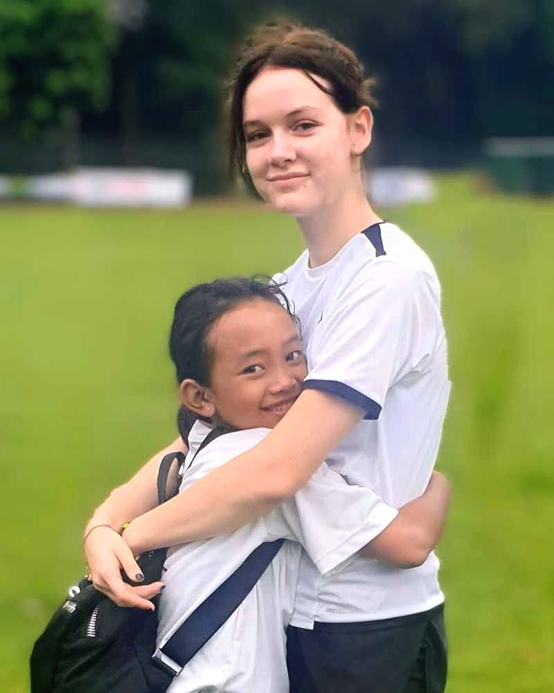 A woman is hugging a little girl in a field