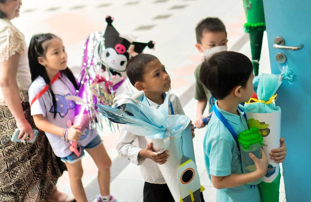 A group of children are standing in front of a blue door holding cones.
