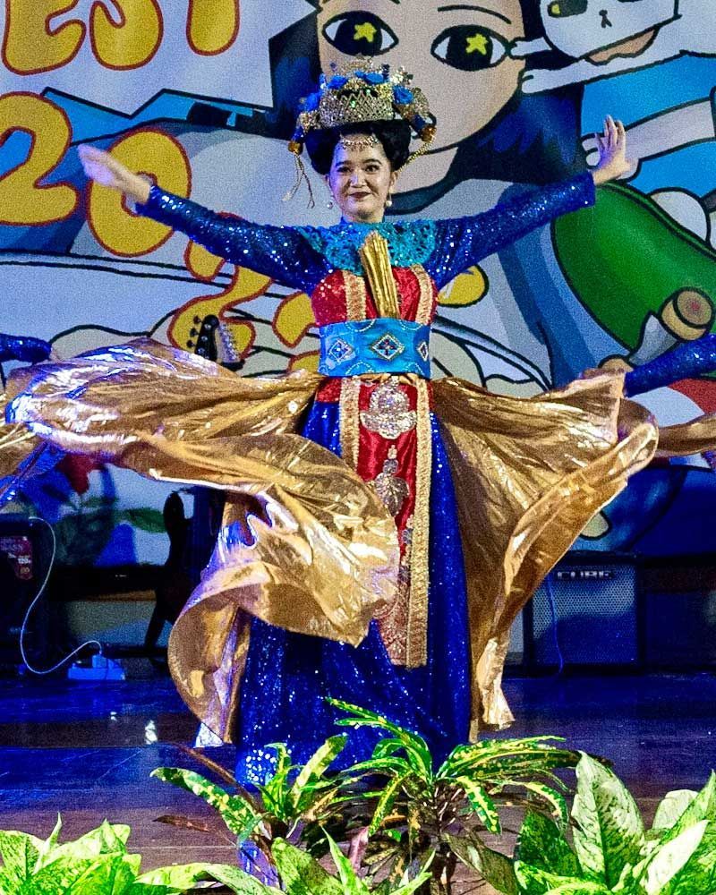 A woman in a blue and gold dress is dancing on a stage