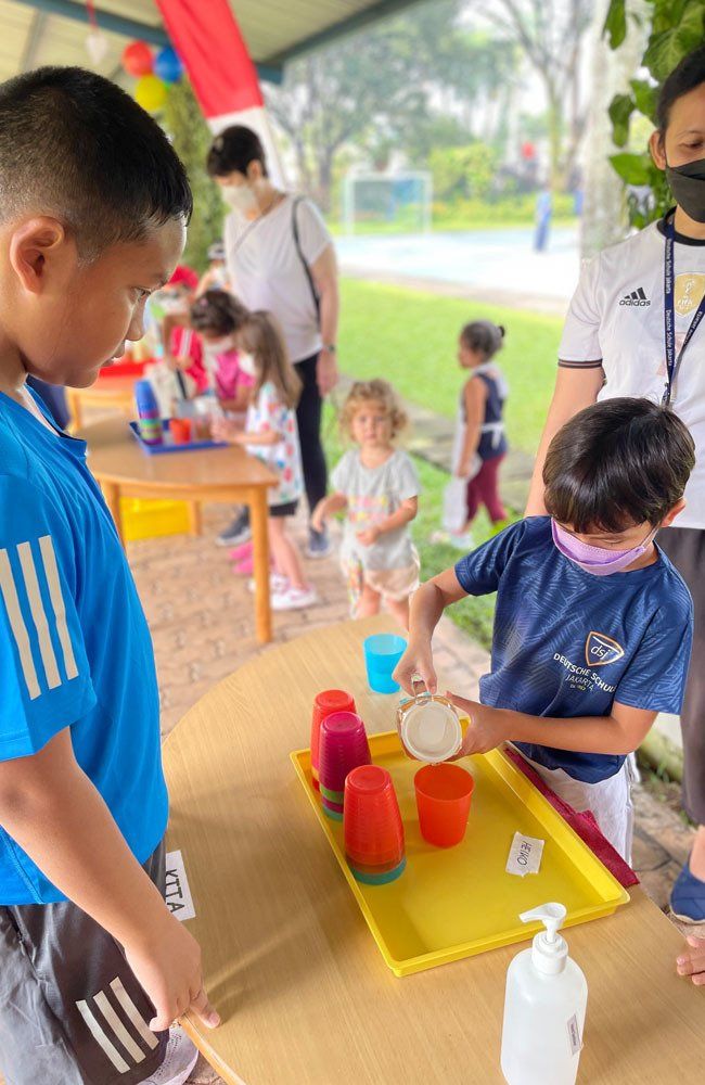 A group of children are playing with cups on a table.