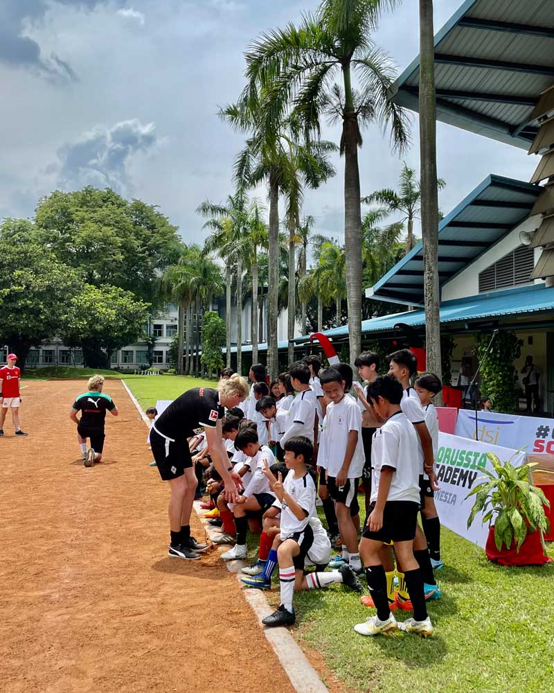 A group of children are playing soccer on a dirt field.