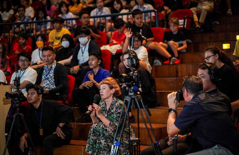 A group of people are sitting in a stadium with cameras.