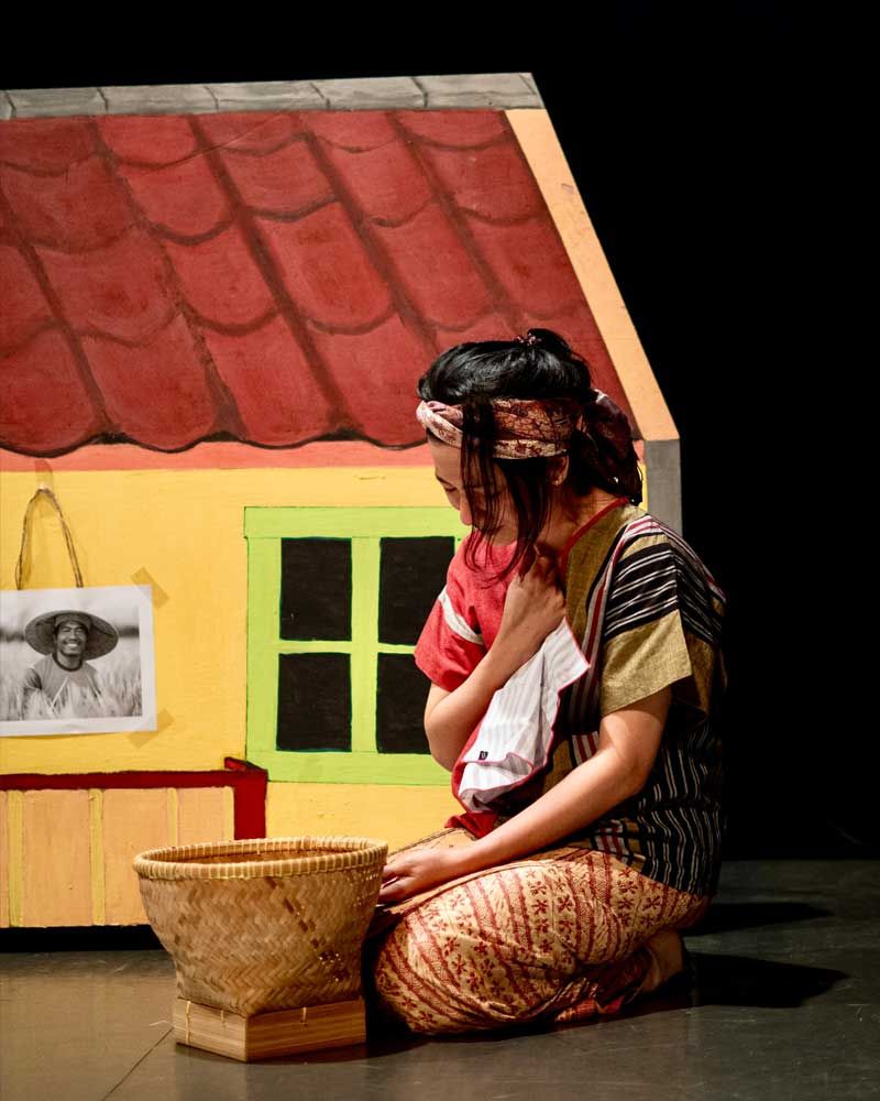 A woman is kneeling down with a child in front of a yellow house