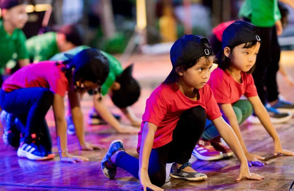 A group of young children are doing exercises on a dance floor.