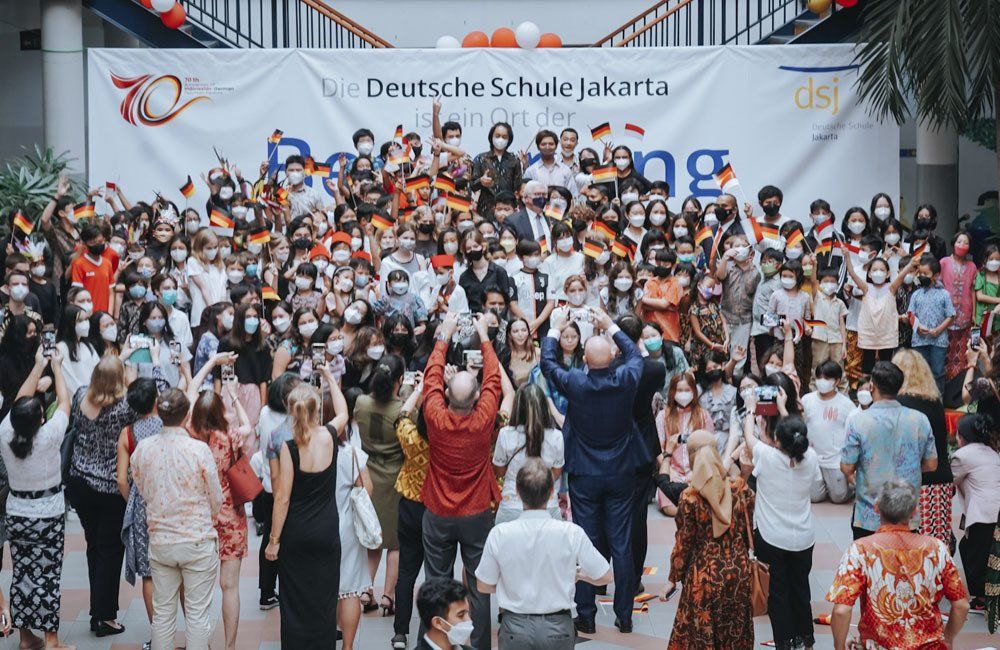 A large group of people are standing in front of a large banner.
