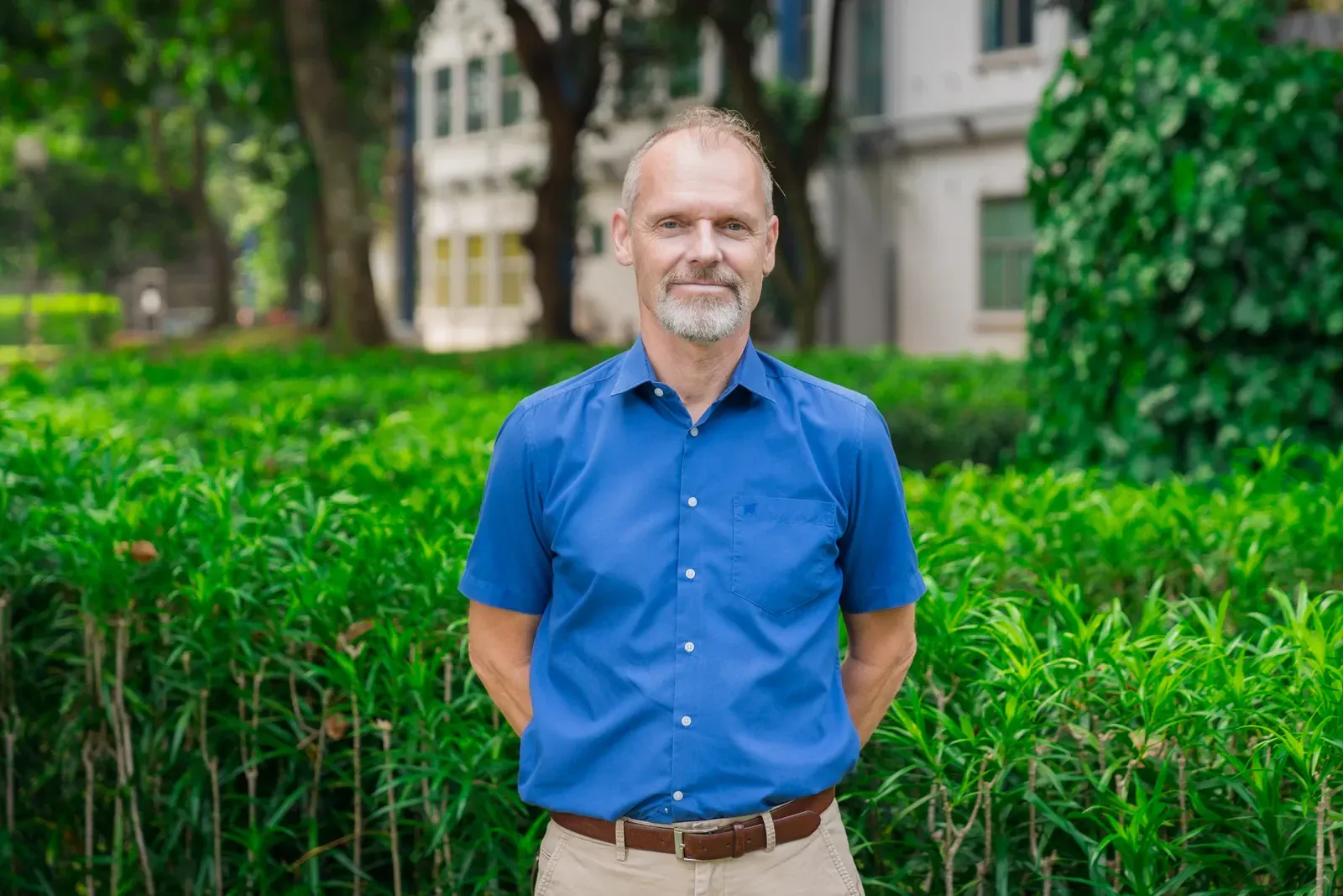 A man in a white shirt is standing with his hands on his hips