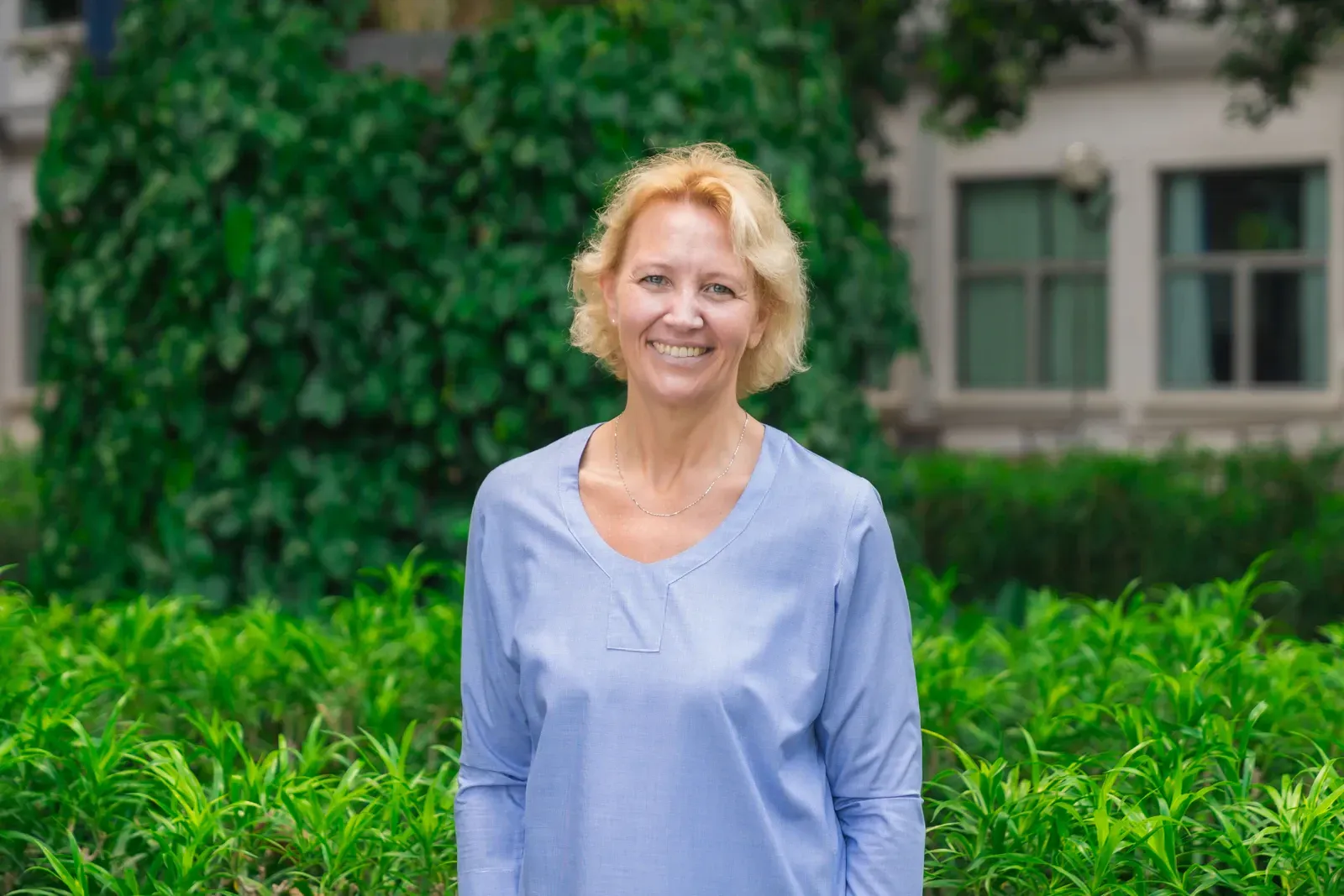 A woman in a black shirt is smiling in front of a building.