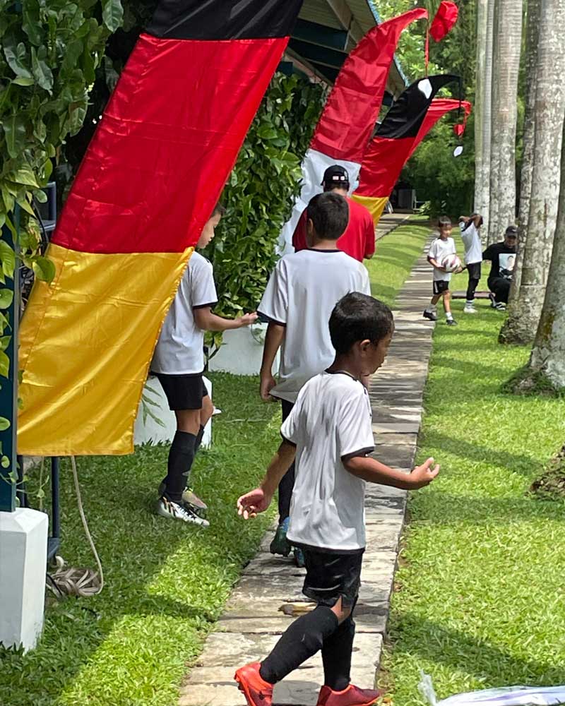 A group of people are walking down a path with flags hanging from the trees.